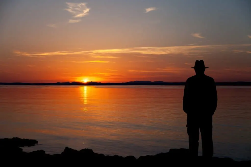 Old man with a hat on watching the sunset in Galway bay in Ireland. 