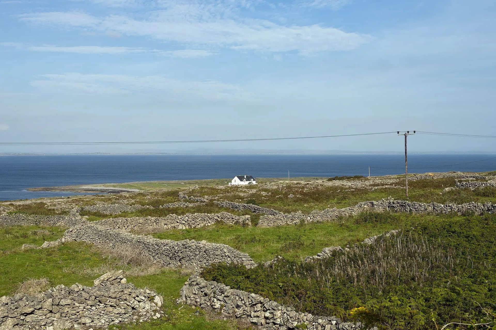 Small white house on the Aran islands. Tiny stone walls surrounding it looking out to sea. 