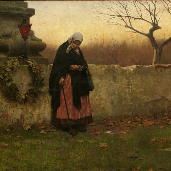 Painting of an elderly woman in a headscarf, dark shawl and red striped skirt, leaning on a walking stick beside a cemetery wall hung with a wreath, with a red lantern on a stone monument, fallen autumn leaves and a bare tree