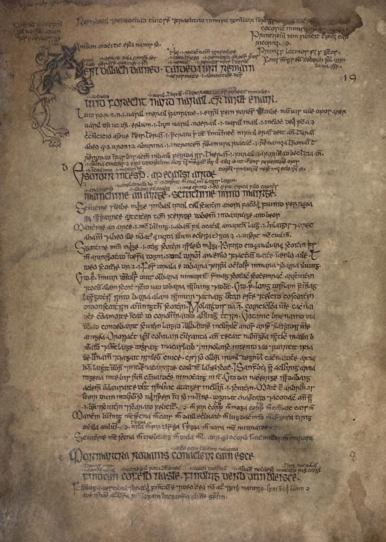 Stained brown manuscript page in Irish script, with a decorated initial, large lines of verse and smaller notes written between and around them