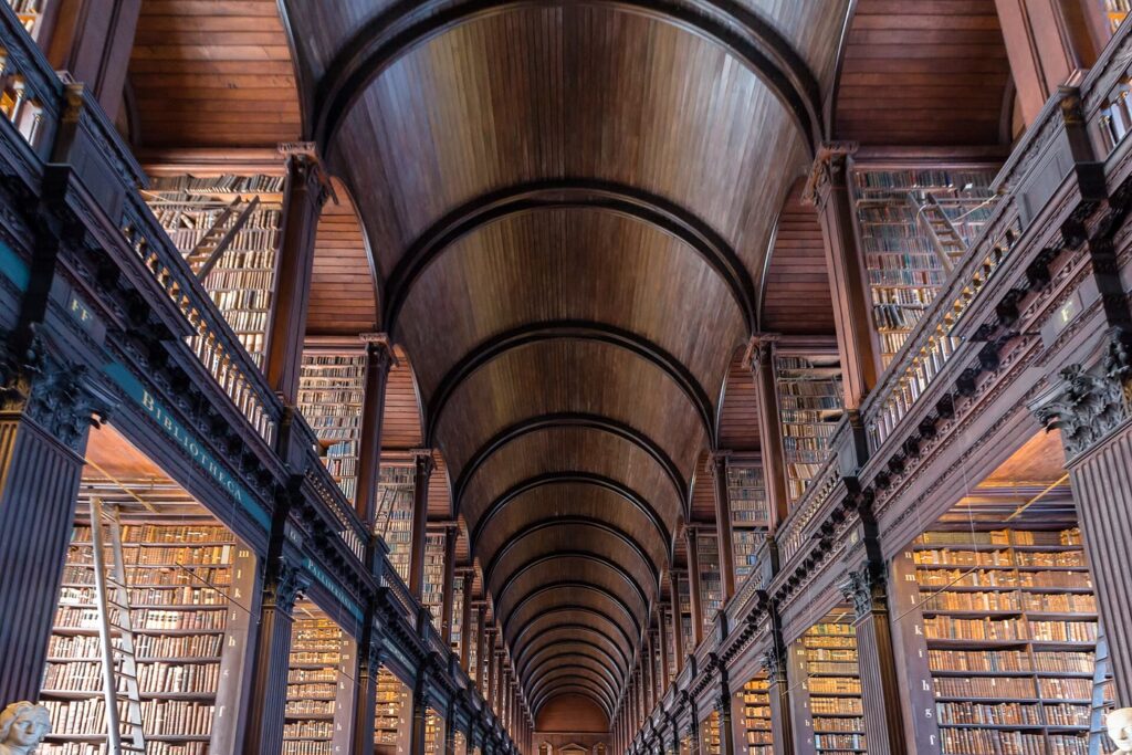 Book of Kells visit: the Long Room of Trinity College Dublin's Old Library, a long barrel-vaulted wooden hall lined on two levels with tall bookcases full of old books