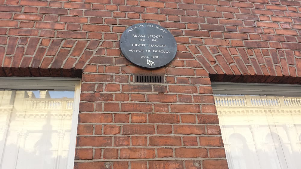 Round dark grey plaque on a red brick wall reading Dublin and East Tourism, Bram Stoker 1847 to 1912, Theatre Manager, Author of Dracula, lived here