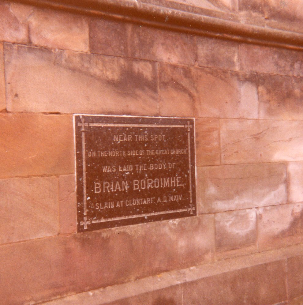 Dark stone plaque on the sandstone wall of St Patrick's Cathedral, Armagh, saying the body of Brian Boroimhe, slain at Clontarf in 1014, was laid near this spot