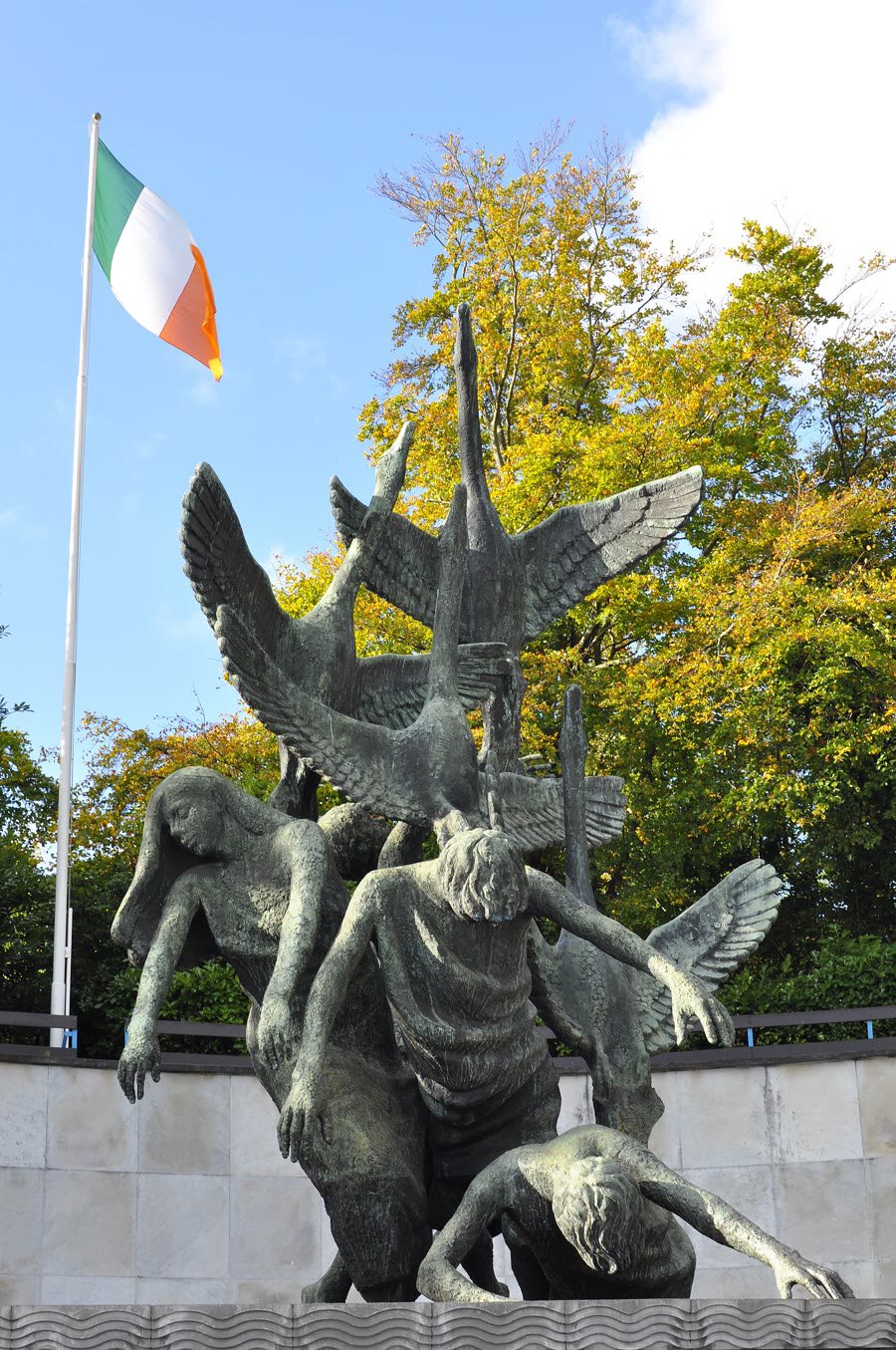 Oisín Kelly's Children of Lir: bronze figures falling beneath four swans with outspread wings, with the Irish tricolour flying behind, Garden of Remembrance, Dublin