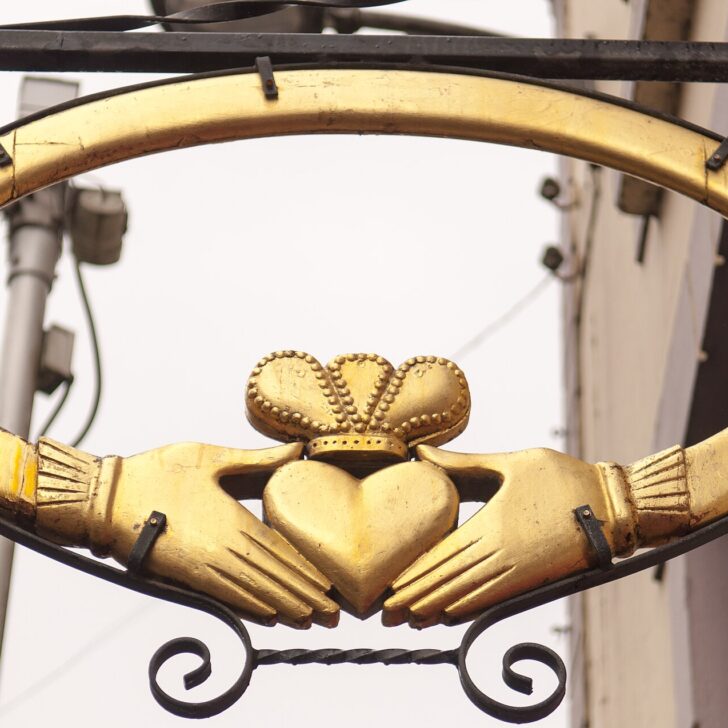 A golden Claddagh sign showing two hands holding a crowned heart