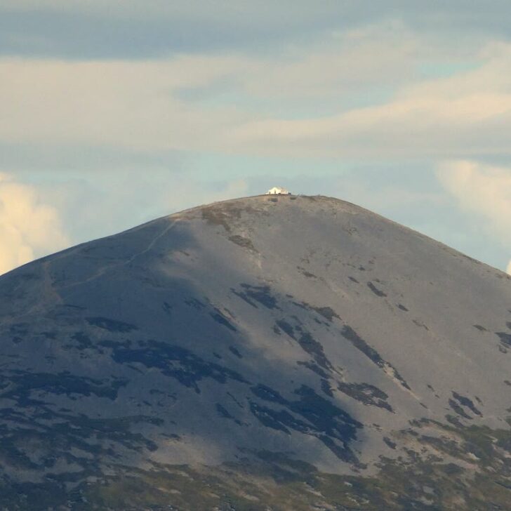 Croagh Patrick: the grey cone of Ireland's holy mountain with the small white summit chapel on top, against a cloudy sky