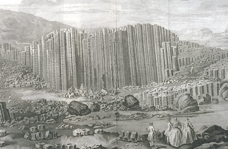 18th-century engraving of the Giant's Causeway: a wall of tall stone columns rising behind a shore scattered with broken column sections, with visitors in 18th-century dress strolling in the foreground (750 px wide only: place at its natural width)
