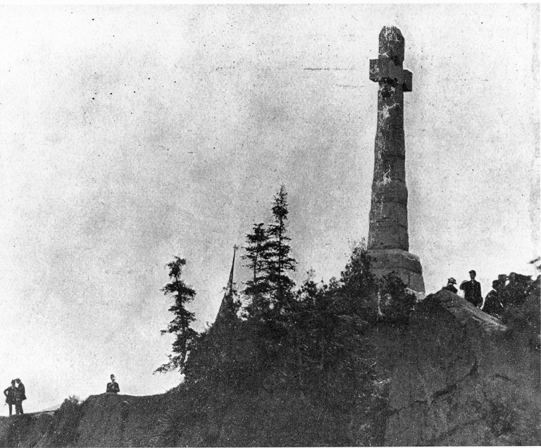 Old photograph of the tall Celtic cross on a rocky height at Grosse &Icirc;le, Quebec, raised in 1909 for the Irish emigrants who died there in 1847