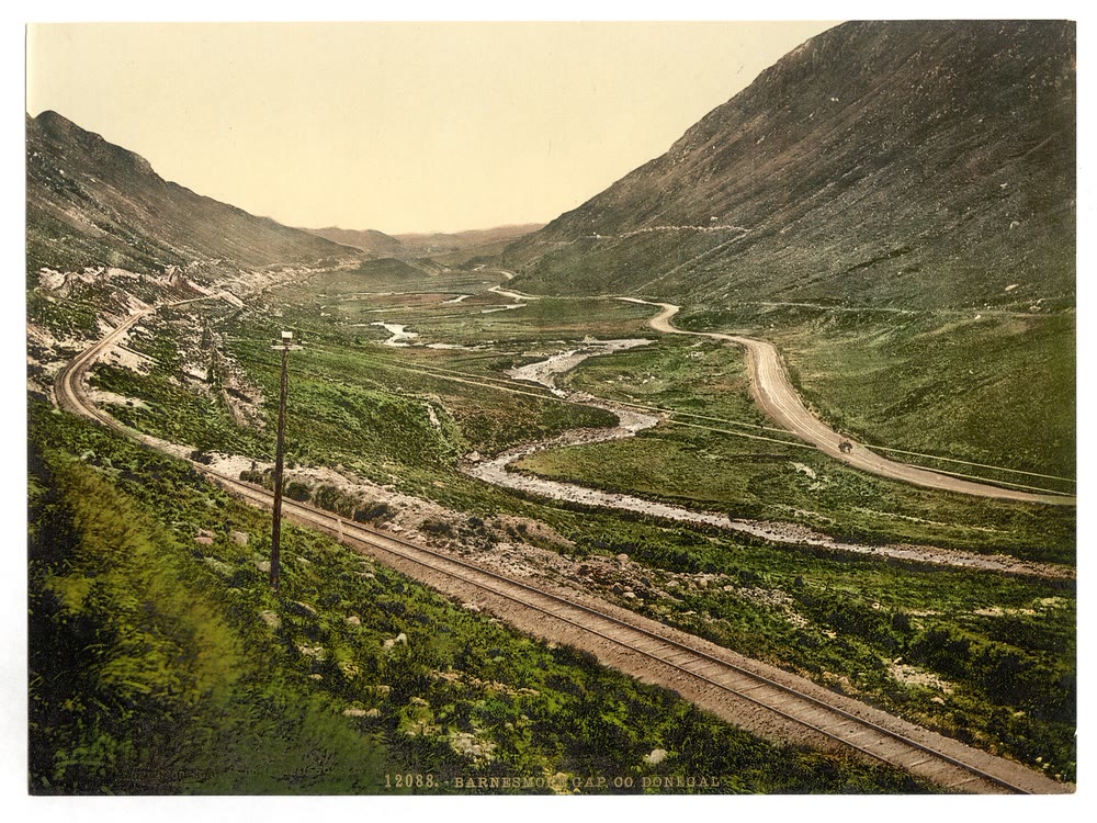 Hand-coloured 1890s view of a road and a railway winding through the green mountain pass of Barnesmore Gap in Co. Donegal