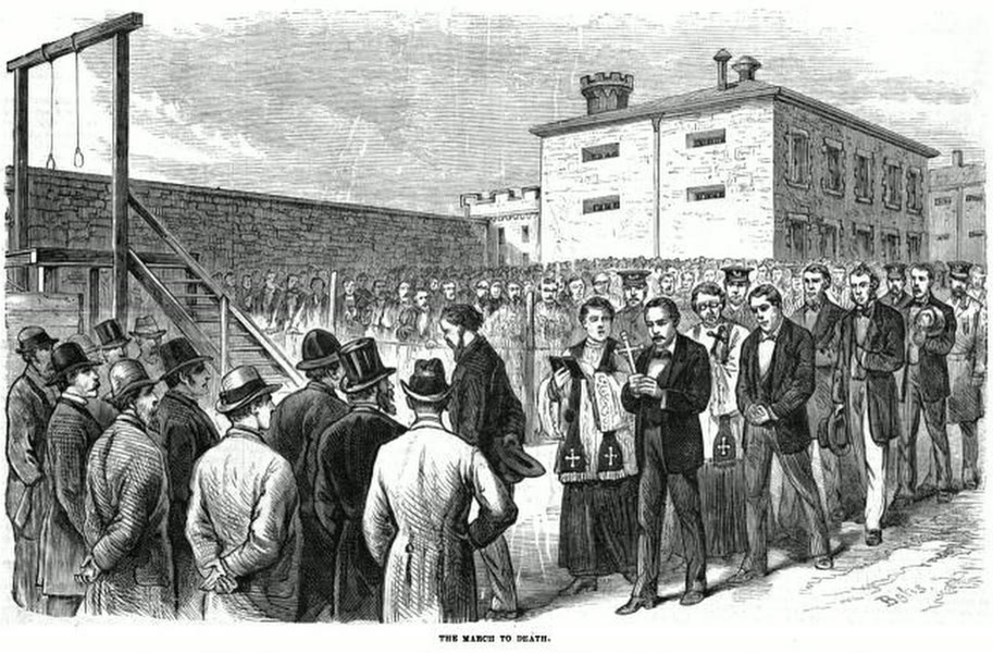 1877 wood engraving of condemned men walking with priests holding a crucifix and prayer book across a crowded prison yard towards a gallows