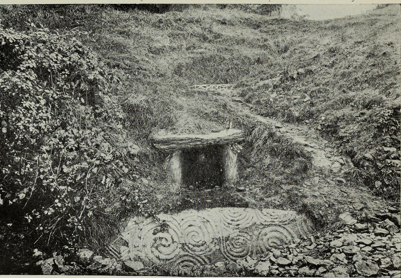 Early 1900s photo of the Newgrange entrance before restoration: the carved entrance stone and a small doorway half buried in ivy and loose stones